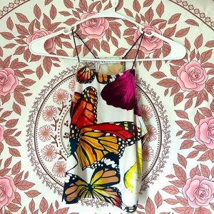 A cropped, spaghetti strap, racer back style top, white and a butter fly print.